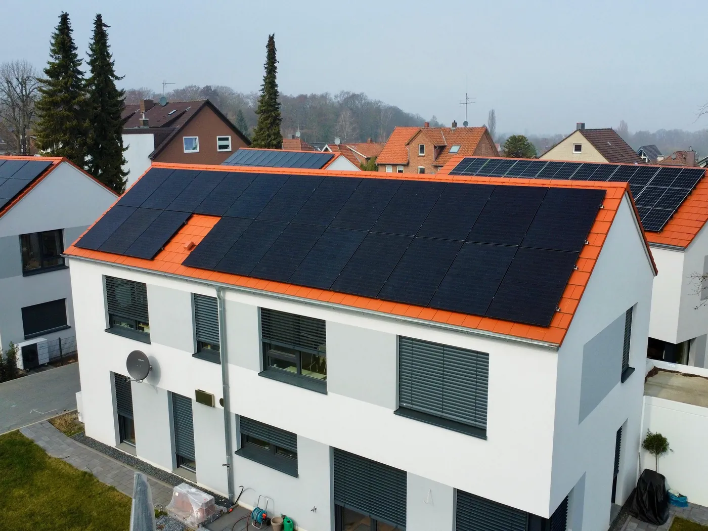 Weißer Neubau mit voll belegter Dachseite aus schwarzen Solarmodulen